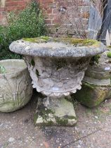 A nicely weathered reconstituted stone garden urn on stand, having relief moulded decoration