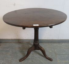 A Georgian elm tilt-top circular occasional table, on a tapered oak pedestal with splayed tripod