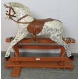 A vintage rocking horse on stand, hand-painted in dapple grey with leather saddle and bridle.
