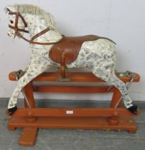 A vintage rocking horse on stand, hand-painted in dapple grey with leather saddle and bridle.