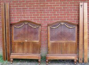 A pair of antique French bergère and fruitwood single beds, the headboards with moulded cornices
