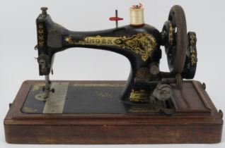 A late Victorian singer sewing machine, circa 1901. Painted black with gilt scrolling foliate