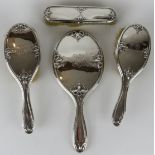 A four piece Art Nouveau silver backed vanity set comprising two hair brushes, clothes brush and a