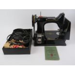 A Singer Featherweight Model 221K1 portable electric sewing machine. The black Model 221K1 sewing