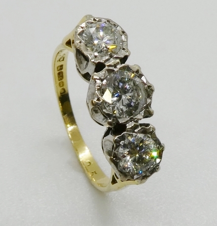 A three stone diamond ring, the graduated round brilliant cut diamonds illusion set in platinum