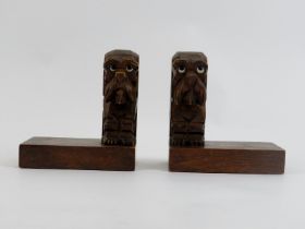 A pair of Black Forest dog bookends, early 20th century. The carved wood seated dogs modelled with