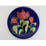 A rare Walter Moorcroft ’Tulips’ pattern plate. Tubeline decorated with flowers against a blue