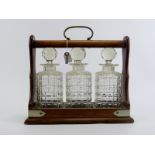 An oak tantalus with three glass decanters, late 19th/early 20th century. 34.7 cm length, 31.5 cm