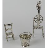 Three miniature continental silver ornaments in the form of a pail, spinning wheel and a chair.