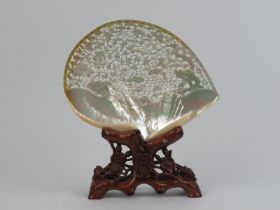 A large Chinese carved and pierced mother of pearl shell mounted on a carved wood stand, mid/late