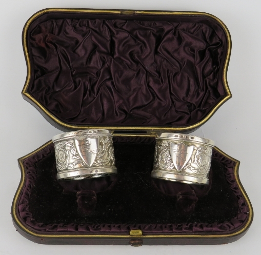 A boxed pair of late Victorian silver napkin rings with floral and foliate decoration. Hallmarked