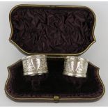 A boxed pair of late Victorian silver napkin rings with floral and foliate decoration. Hallmarked