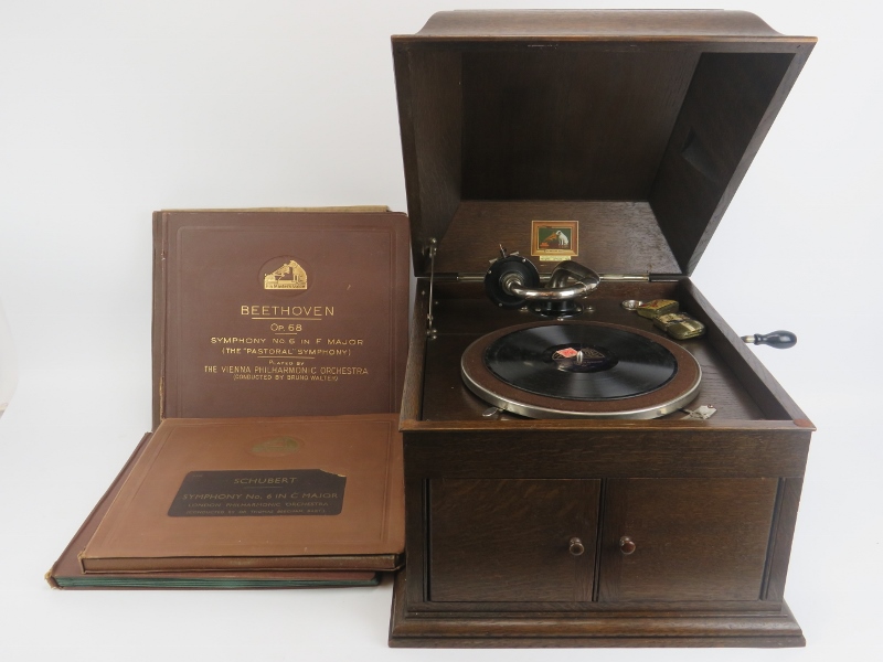 A vintage His Masters Voice oak cased wind up gramophone with four classical 78 albums. (5 items)