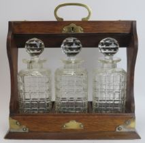 A brass mounted oak tantalus with three glass decanters, late 19th/early 20th century. 34.8 cm