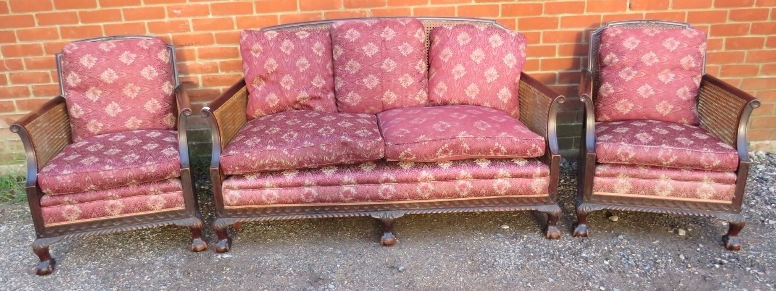 An antique mahogany bergère three-piece suite, comprising a two-seater sofa and two armchairs,