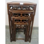 A vintage Chinese hardwood nest of four graduated tables, having carved and pierced frieze