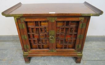 An antique Chinese elm apothecary cabinet with brass mounts, the tracery doors opening onto a