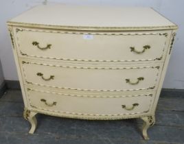 A vintage French bow-fronted chest in the Louis XV taste, painted cream and gold, housing three long