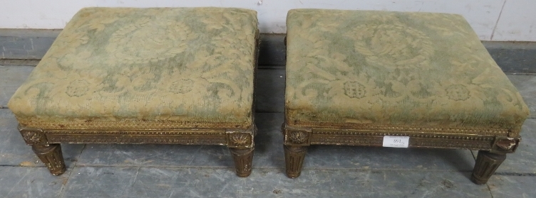 A pair of Regency Period giltwood footstools, retaining the original upholstery, on fluted