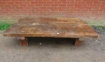 A heavy rustic oak coffee table, constructed of medieval timber, the planked top raised on block