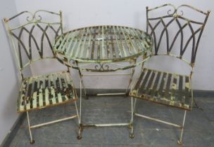 A vintage garden set painted pale green, comprising two folding chairs with slatted seats and a