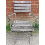 A weathered teak folding garden elbow chair with slatted seat. H90cm W59cm D81cm (approx). Condition