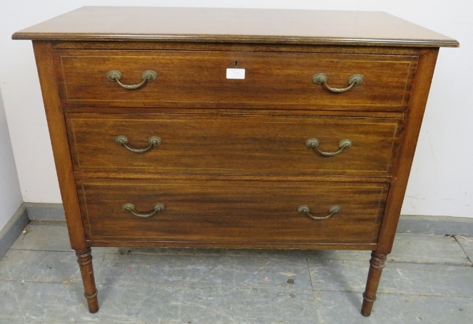 An Edwardian mahogany chest housing three long drawers with fancy brass handles and inlaid brass