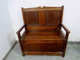 An Art Deco Period oak settle, the back with geometric carved frieze decoration, above a box base