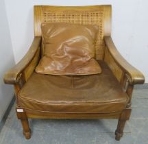 An antique style fruitwood armchair, having double skin bergère back and sides, with loose
