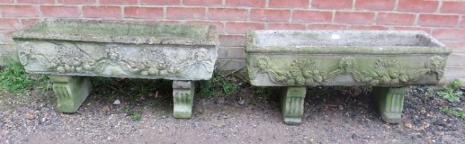 A pair of weathered reconstituted stone trough planters, having relief decoration depicting lion