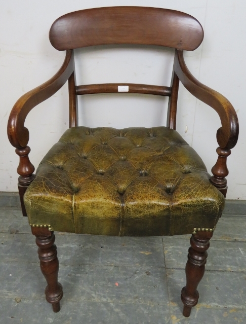 An early Victorian mahogany desk chair upholstered in antique buttoned brown leather with brass