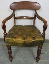 An early Victorian mahogany desk chair upholstered in antique buttoned brown leather with brass