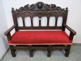A 19th century Gothic revival oak hall bench, having turned finials and profuse acanthus leaf
