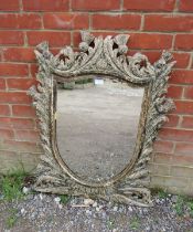 A 19th century shield-shaped wall mirror, within an ornate carved wooden surround depicting