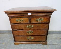 A diminutive 18th century oak chest, housing two short over three long graduated cock-beaded drawers