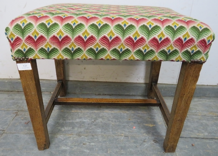 A rustic 19th century oak stool, reupholstered in multi-coloured woollen material with brass