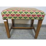 A rustic 19th century oak stool, reupholstered in multi-coloured woollen material with brass