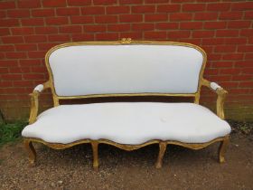 A 19th century French giltwood three-seater sofa, having a serpentine front, reupholstered in calico