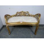 An antique French kidney shaped giltwood window seat, having ornately carved and pierced back and
