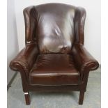 An antique style wingback armchair, upholstered in brown leather, on reeded square supports.