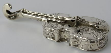 A silver box in the form of a violin with embossed decoration depicting putti in rural scenes.