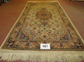 A Persian design rug, central motif, surrounded by repeat fawn, cream & brown. 176cm x 94cm (