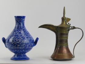 A Middle Eastern copper and brass dallah and a Moroccan blue and white twin handled ceramic vase. (2