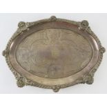An ornate George III oval silver salver standing on four foliate feet and having a gadrooned,
