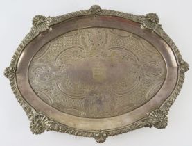 An ornate George III oval silver salver standing on four foliate feet and having a gadrooned,