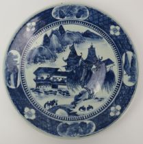 A Chinese blue and white porcelain charger, 19th century. Painted depicting a lakeside pavilion with