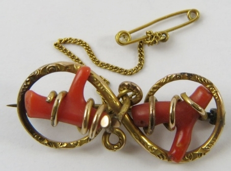 A Late Victorian gold and coral brooch, of figure of eight design, with pin clasp and safety