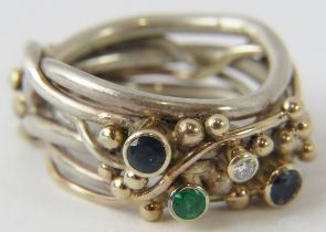 A silver and gold artisan designed ring with 2 inset sapphires, an emerald and a single diamond.