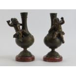 A pair of French patinated bronze vases modelled with angels, 19th century. Mounted on red marble