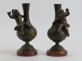 A pair of French patinated bronze vases modelled with angels, 19th century. Mounted on red marble
